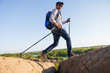 © snedorez - Picture of tourist man with walking sticks walking in mountainous area