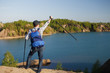 © snedorez - Image from back of young tourist with backpack with arms raised with walking sticks on background of mountain landscape