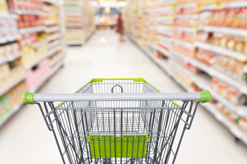 Supermarket aisle with empty shopping cart at grocery store retail business concept