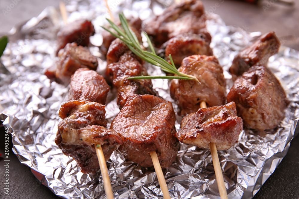 Barbecue skewers with juicy meat on foil