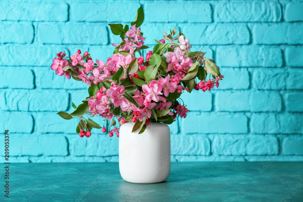 Vase with beautiful blossoming branches on table