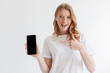 © Drobot Dean - Happy young redhead woman showing display of mobile phone pointing.