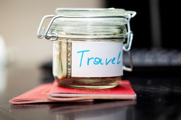 Holidays money savings in a glass jar. Two passports are next to money box. Journey or travel concept