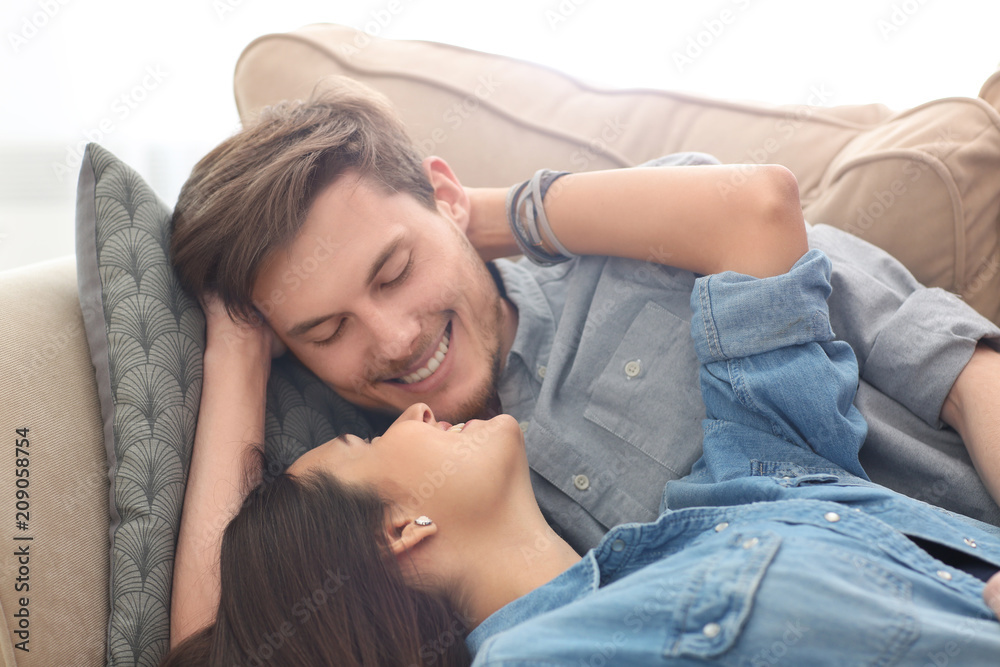 Happy young couple resting on sofa indoors