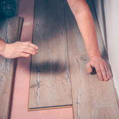 Working with hands installs a laminate board, professional flooring installation