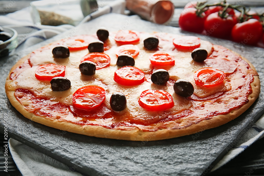 Slate plate with tasty Italian pizza on table