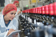 Woman making notes beside bottling plant production line