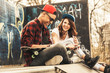 Young teen couple sitting by the wall and hangout at the street .Embrace each other and laughing .