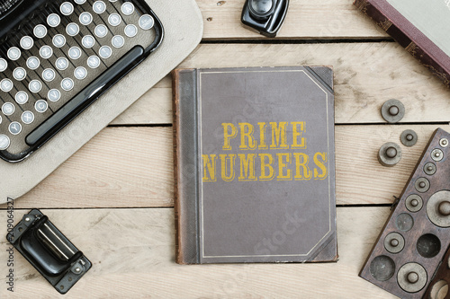 Fotografía Text Prime Numbers on old book cover at office desk with vintage items