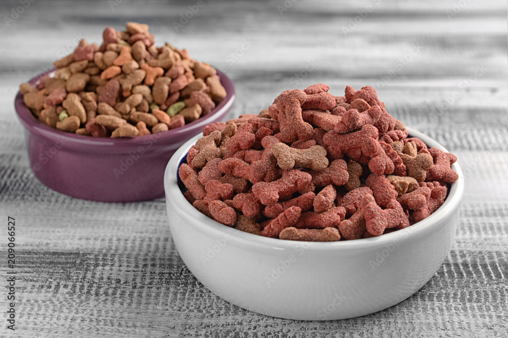 Bowls with pet food on wooden background