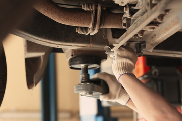 Auto mechanic repairing car in service center, closeup