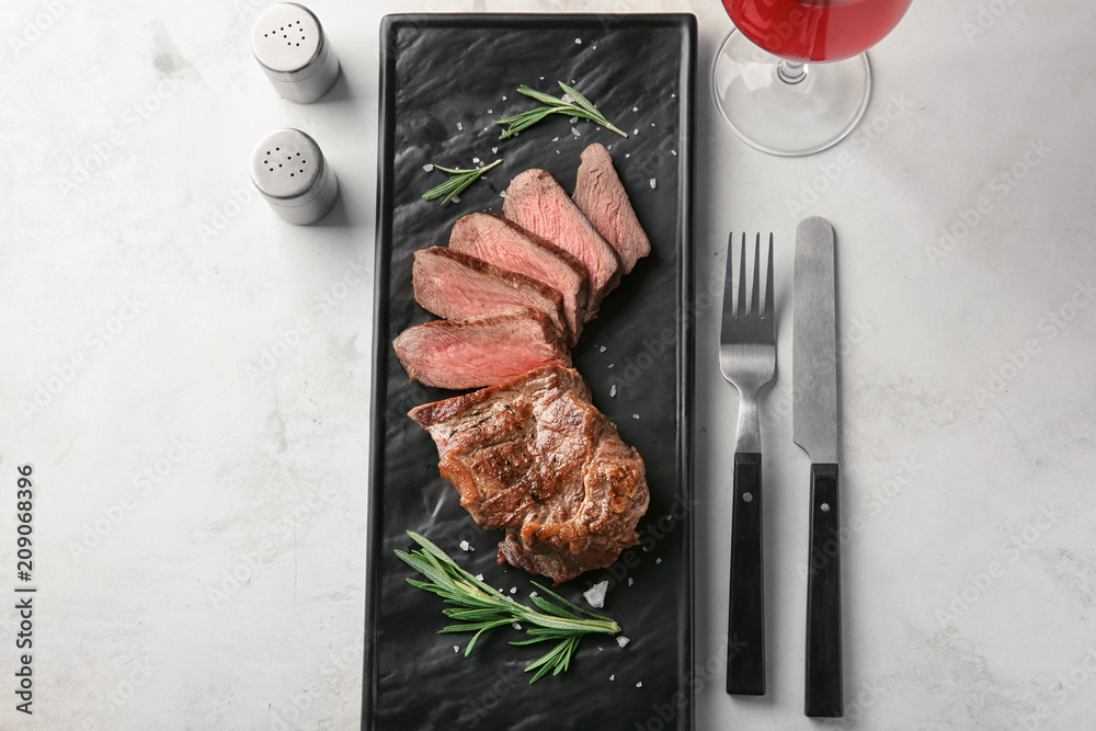Composition with tasty grilled steak on light background