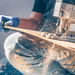 Wall Mural - The electric jigsaw in the hands of the worker, the sawdust and dust are flying beautifully, shooting in motion