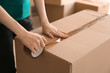 Woman packing carton box indoors. Moving house concept