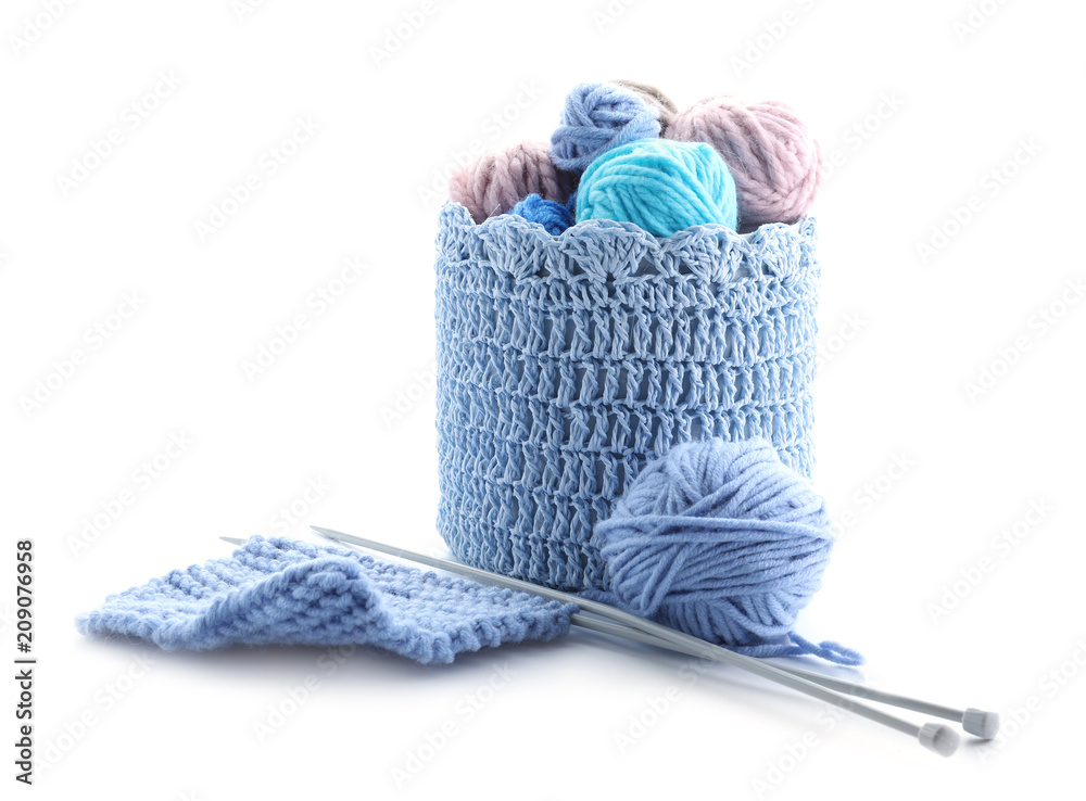 Basket with knitting yarn and needles on white background