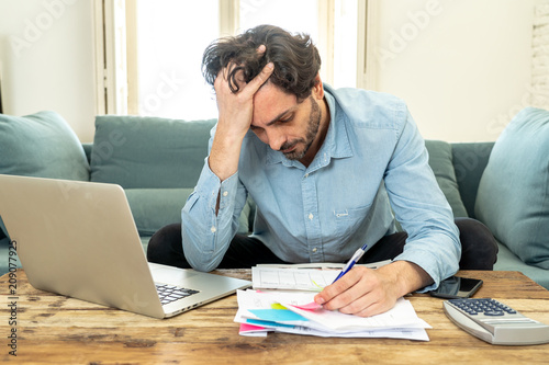 Fotomural angry man paying bills as home with laptop and calculator