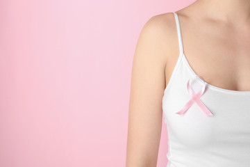 Woman with pink ribbon against color background. Breast cancer awareness concept