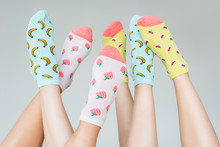 Partial View Of Female Feet In Colorful Fruity Socks, Isolated On Grey
