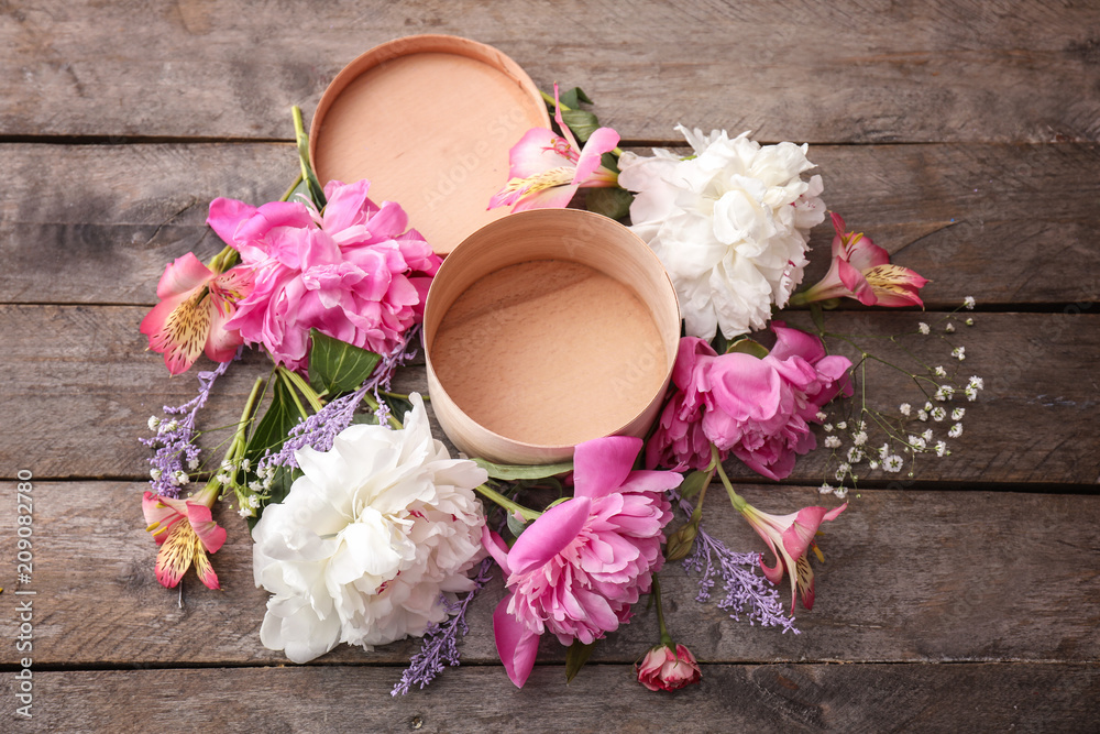 Gift box and beautiful flowers on wooden table