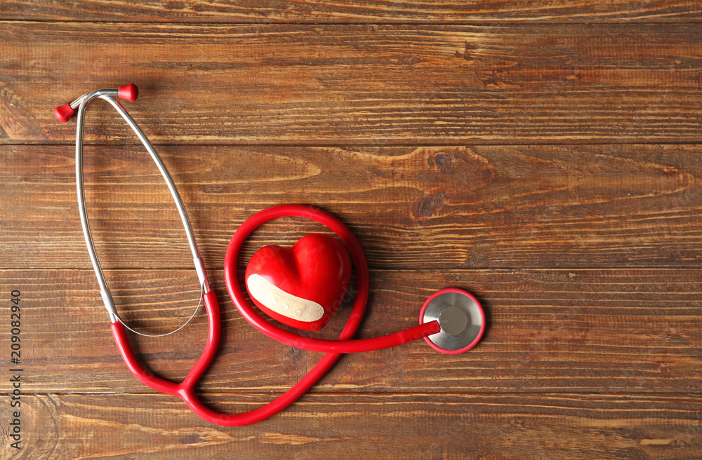 Red heart and stethoscope on wooden background. Health care concept