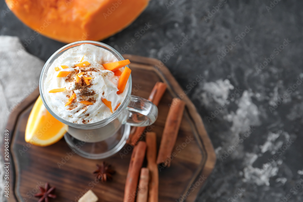 Glass cup of latte with pumpkin and cinnamon on board