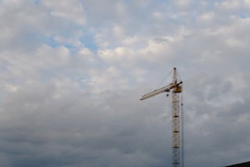 Big tower cranes above buildings under construction against blue sky. Background image of construction close-up with copy space. Build of city.