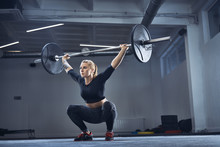 Woman Doing Overhead Squat Exercise At Gym