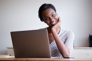 woman resting head on hand sitting at desk with laptop