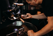 Man Working At Coffee Production. Barista Controling Coffee Grounds Roasting Process.
