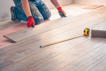 Working with hands installs a laminate board, professional flooring installation