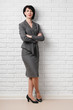 © soleg - business woman dressed in a gray suit poses in front of a white wall