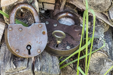 two vintage rusty metal hinged lock with a key against the background of the virgin boards