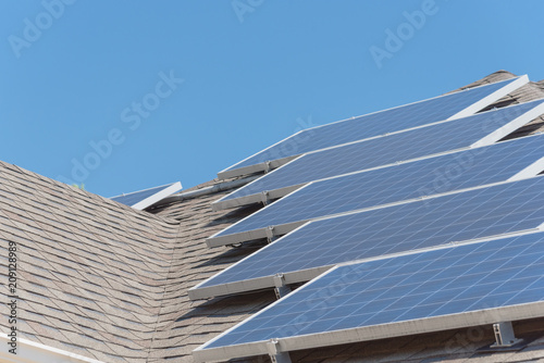 Close-up rail-less racking solar panel system on asphalt shingles rooftop commercial building. Battery storage bracket installation at Grapevine, Texas, USA. Renewable clean energy concept background