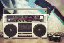 Retro Boombox Radio With Cassettes On A Graffiti Background / Vintage Ghetto Blaster With Plenty Of Musical Cassettes On Grungy Background With Graffiti. 