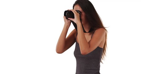 Wall Mural - Pretty travel photographer wearing striped top taking photo with dslr camera, Creative young woman focusing lens on camera and taking snapshot on white background, 4k