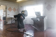 © liorz/Stocksy - Man cleaning under machinery using steam from power hose