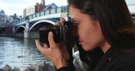 Wall Mural - Side view of hipster girl taking photo of River Thames with dslr camera, Millennial woman in England taking scenic photograph of swans by Windsor Town Bridge, 4k