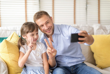 Happy holiday. Smart dad is take a photo with his cute daughter. They are show victory. Setup studio shooting.