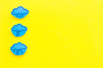 Wall Mural - rainfall forecast concept. weather icons. rainy cloud, lightening on yellow background top view copy
