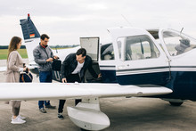 Caucasian Passengers Loading Luggage Into Small Private Airplane