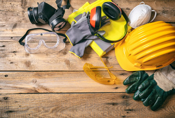construction safety. protective hard hat, headphones, gloves and glasses on wooden background, copy 