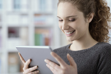 Smiling girl watching videos on her tablet