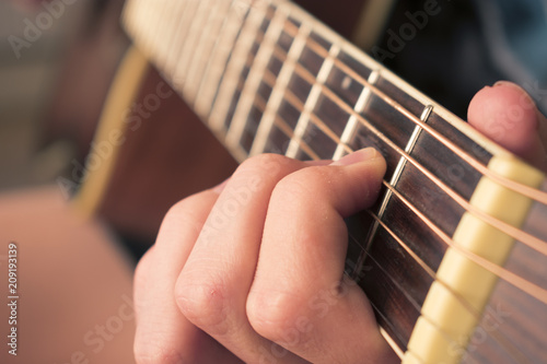 Fotografie, Obraz Female hand playing on acoustic guitar. Close-up.