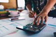 © nopparat - Businessman or accountant using pen and calculator for audit budget and finance of company on wooden desk in office.Auditor financial or bookkeeper concept.