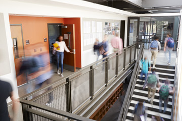 busy high school corridor during recess with blurred students and staff