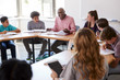 © Monkey Business - Male High School Tutor Sitting With Students At Desk In Class