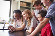 © Monkey Business - Group Of High School Students Looking At Message On Mobile Phone In Classroom