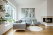 Leinwandbild Motiv Spacious white living room interior with grey corner couch, big modern art painting and fireplace
