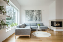 Spacious White Living Room Interior With Grey Corner Couch, Big Modern Art Painting And Fireplace