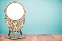 Old Antique Vintage Cast Iron Desk Makeup Mirror Frame Blank In The Form Of Goddess With Wings Or Angel Standing On Table Front Turquoise Wall Background. Circa 1800s Or Early 1900s. Retro Style Photo